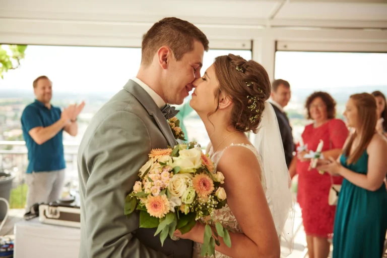 Ein Paar kurz vor dem ersten Kuss bei ihrer Hochzeit. Sie stehen sich eng gegenüber, die Nasen berühren sich bereits. Die Braut steht rechts und hält einen Blumenstrauß. Hochzeitsfotograf Kaiserslautern